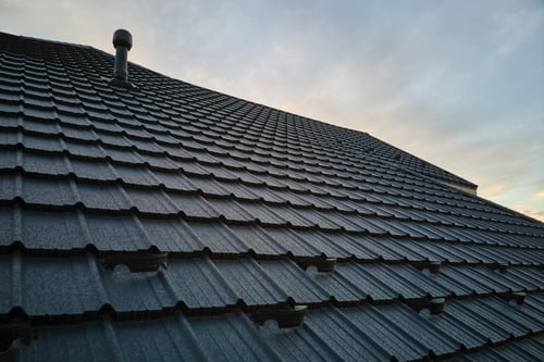 Dark tile roof installed on a home under a clear sky